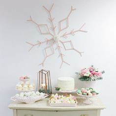 a table topped with cakes and cupcakes next to a wall mounted snowflake