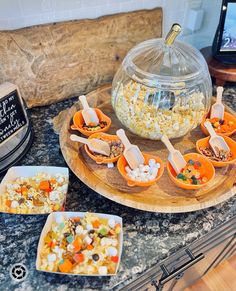 bowls and spoons filled with food sitting on a counter next to a bowl full of popcorn