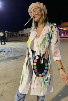 a woman standing on top of a sandy beach holding a paintbrush in her mouth