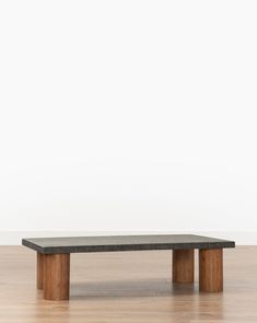 a wooden table sitting on top of a hard wood floor next to a white wall