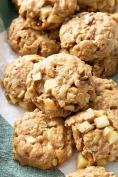 oatmeal cookies with apples and nuts are on a paper lined tablecloth