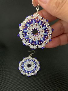 someone is holding some kind of beaded earrings in their hand and it looks like they are making something out of beads