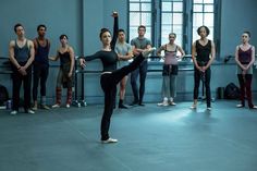 a group of people standing around each other in front of a ballerina and ballet instructor