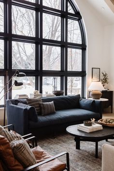 a living room filled with furniture next to a large window covered in lots of windows