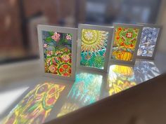 four colorful cards sitting on top of a table next to each other with different designs