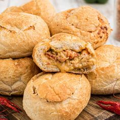 a pile of bread rolls sitting on top of a cutting board next to hot peppers