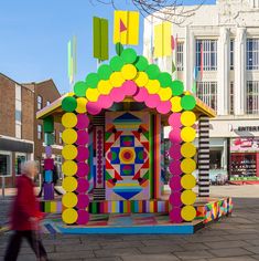 a brightly colored structure on the street with people walking by