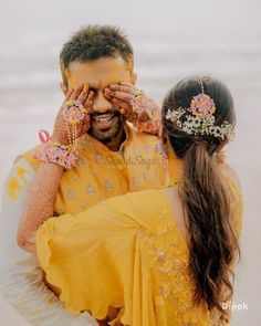 a man and woman standing next to each other with their hands covering their eyes while they both look at the camera