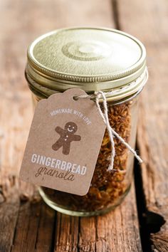 a jar filled with gingerbread granola sitting on top of a wooden table next to a tag