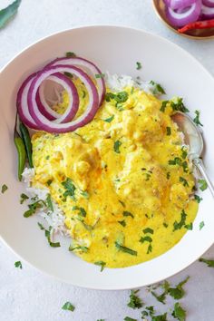 a white bowl filled with eggs and onions on top of rice next to onion slices