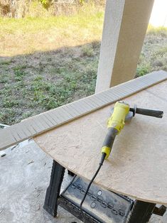 an electric sanding machine sitting on top of a wooden table next to a building