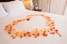 a bed with flowers on it in the shape of a heart made out of petals