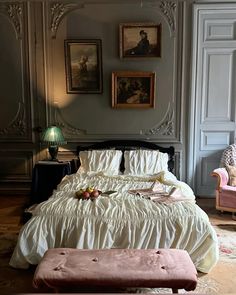 a large bed sitting in a bedroom next to a pink chair and ottoman on top of a hard wood floor