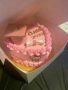 a pink hello kitty graduation cake in a box