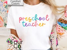 How cute is this colorful teacher tee?! This adorable Comfort Colors shirt comes in all the fun colors! Size up for oversized fit. Refer to size chart for measurement specifics. SIZING: *Unisex sizing *See size chart image for measurements DESCRIPTION: *SWEATSHIRTS: Unisex heavy blend crewneck sweatshirt Loose fit Runs true to size 50/50 cotton/polyester Sewn-in label No side seems *BELLA + CANVAS TEES: Unisex short sleeve tee 100% Airlume combed and ringspun cotton (fiber content may vary for different colors) Light fabric Tear away label Runs true to size *COMFORT COLORS TEES: Unisex short sleeve tee Medium fabric Relaxed fit Sewn-in twill label 100% ring-spun cotton No side seems *KIDS GILDAN TEES Unisex heavy cotton tee Tear away label  Shoulders have twill tape for improved durability Teacher Tshirts Designs Preschool, Name Print T-shirt For Daycare And Back To School, Pre K Shirts For Teaxhers, Cotton T-shirt For Daycare And Back To School, Preschool Teacher Shirts, Graphic Print Short Sleeve T-shirt For Teacher Appreciation, Teacher Tees, Bella Canvas Tees, Preschool Teacher