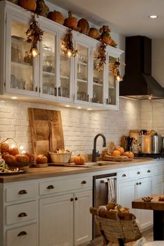 a kitchen filled with lots of white cupboards and counter top covered in pumpkins