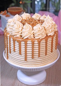 a cake with frosting and caramel drizzled on top sitting on a table