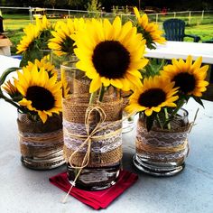 sunflowers in mason jars tied with twine and burlocks on a table