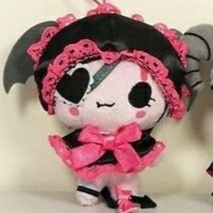 two small stuffed animals are dressed in black and pink outfits, one is wearing a skull headband