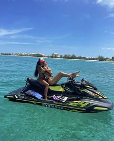 a woman riding on the back of a jet ski in clear blue water next to an island