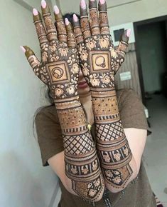 a woman holding her hands up with henna designs on it