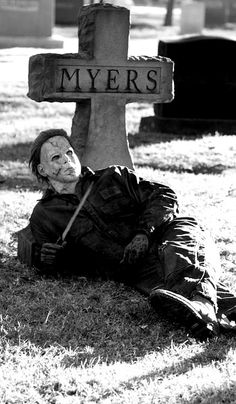 a person laying on the ground in front of a grave with a cross behind them