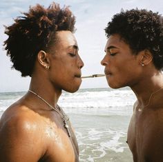 two young men standing next to each other in the ocean with their noses close together