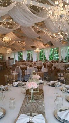 a banquet hall with tables and chairs covered in white draping, chandeliers and flowers