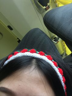 a woman wearing a headband sitting on an airplane with the seat back facing her