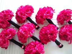 pink flowers are arranged on the side of a white wall with black stems and handles