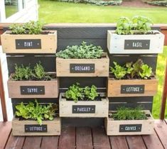 a stack of wooden crates filled with different types of plants and herbs on top of a deck