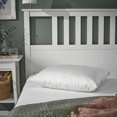 a white bed topped with pillows next to a night stand