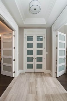 an empty room with white doors and wood flooring in front of the doorways