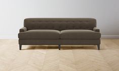 a couch sitting on top of a hard wood floor next to a white wall and wooden floors