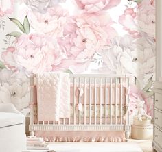 a baby's room with pink and white flowers on the wall, crib