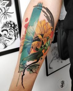 a woman's arm with a sunflower and bird tattoo on the left forearm