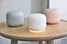 two white and one pink smart devices sitting on a wooden table next to each other