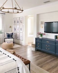 a bedroom with a large flat screen tv mounted to the wall above a blue dresser