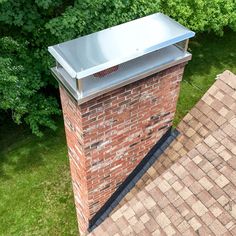 an aerial view of a brick chimney on top of a roof with grass and trees in the background