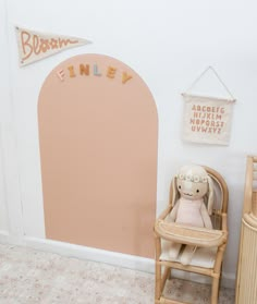 a teddy bear sitting in a chair next to a wall with a name on it