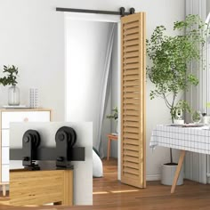 an open door in a white room next to a table with plants and other items