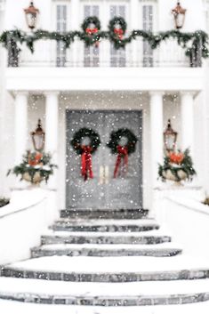 two wreaths are on the front steps of a house in the snow with christmas decorations