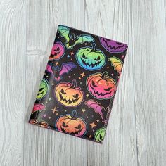 a halloween themed napkin with pumpkins and bats on it, sitting on a wooden surface