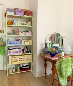 a green shelf filled with lots of items next to a table and chair in a room