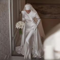 a woman in a white wedding dress is walking down the stairs with her hands on her hips