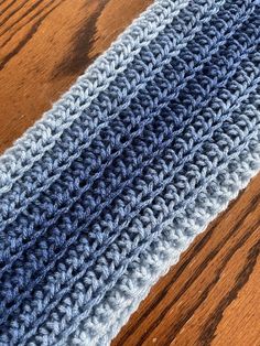 a crocheted blue and gray scarf on a wooden table