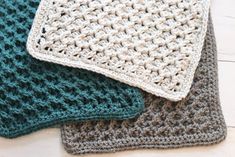 three crocheted dishcloths sitting on top of a white wooden floor next to each other