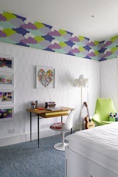 a bedroom with a bed, desk and colorful wallpaper on the walls in it