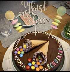 a chocolate birthday cake with an ice cream cone and candies on the top, surrounded by confetti