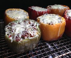 four stuffed peppers sitting on top of an oven grill with cheese and other toppings